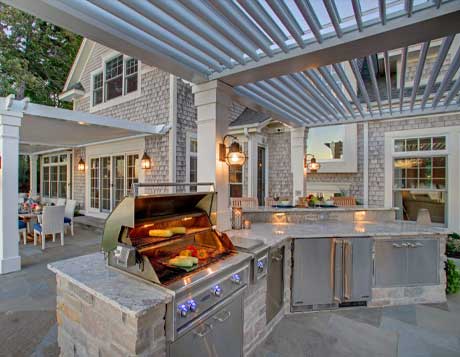 Outdoor kitchen with a StruXure pergola featuring adjustable louvers, a built-in grill, and dining area.
