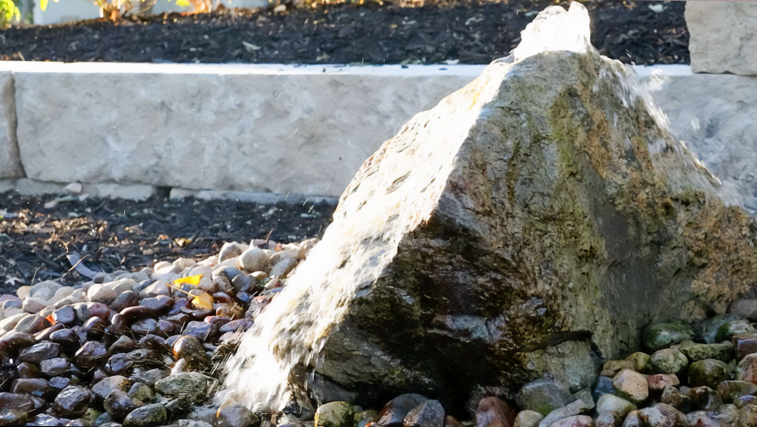 Close-up view of a water feature with a rock fountain and pebbles